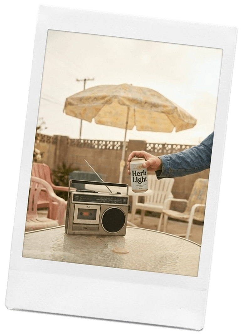 Polaroid of a man holding a can of Herb Light next to a boombox